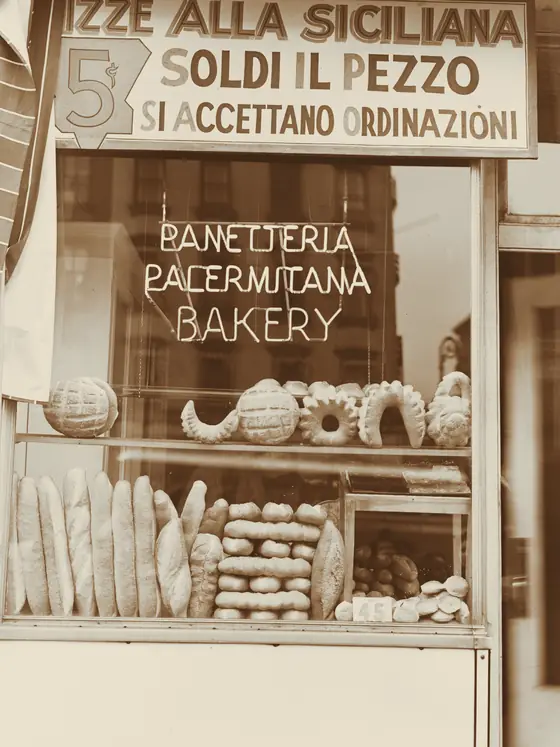 Archival photograph of another bakery: a shop window stacked with loaves, rolls and rings of bread.